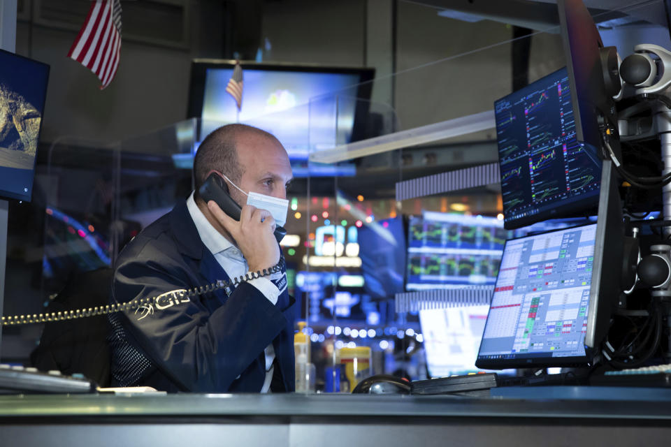 In this photo provided by the New York Stock Exchange, specialist James Denaro works at his post on the trading floor, Thursday Dec. 3, 2020. U.S. stocks are inching further into record heights Thursday, as Wall Street continues to coast following its rocket ride last month powered by hopes for coming COVID-19 vaccines. (Nicole Pereira/New York Stock Exchange via AP)