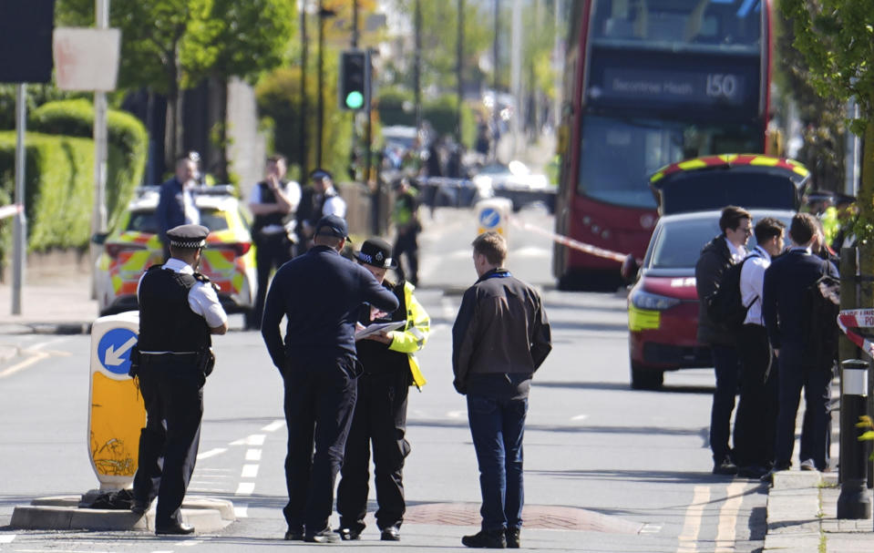 Police talking to members of the public at the scene in Hainault, north east London, Tuesday, April 30, 2024 after reports of several people being stabbed at a Tube station. Police say a man wielding a sword attacked members of the public and two police officers on Tuesday in the east London community of Hainault before being arrested. The incident is not being treated as terror-related. (Jordan Pettitt/PA via AP)