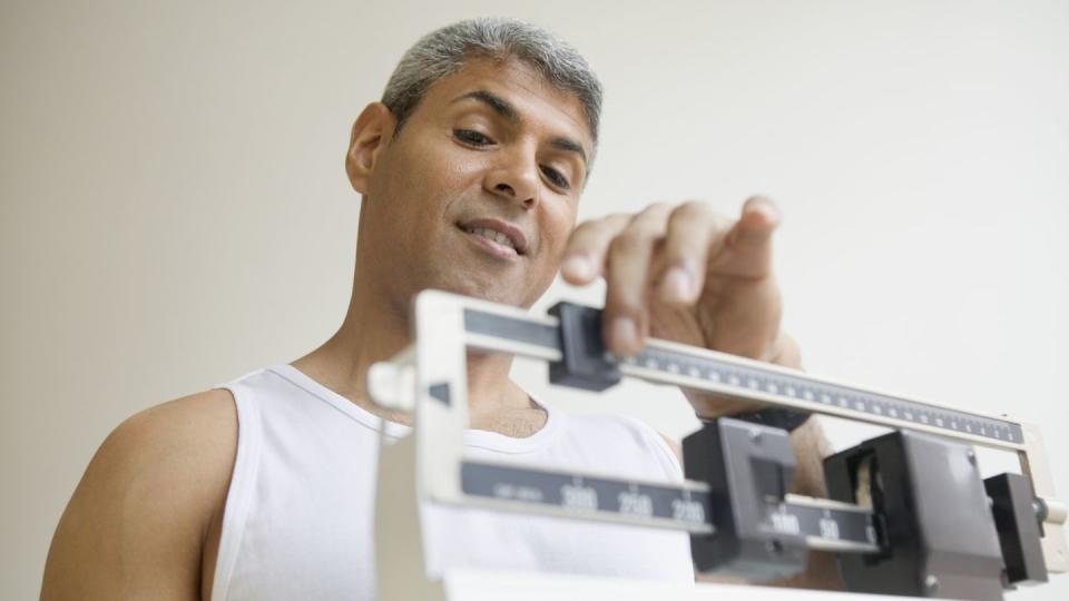 middle aged man weighing himself