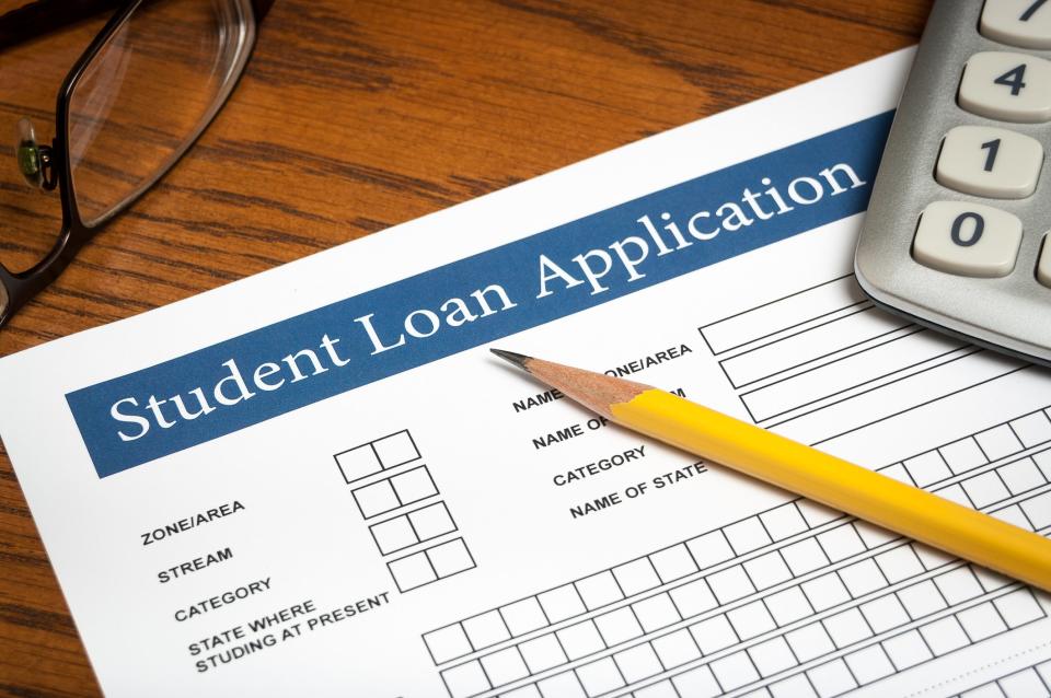 Student loan application on a desk with a pencil and calculator