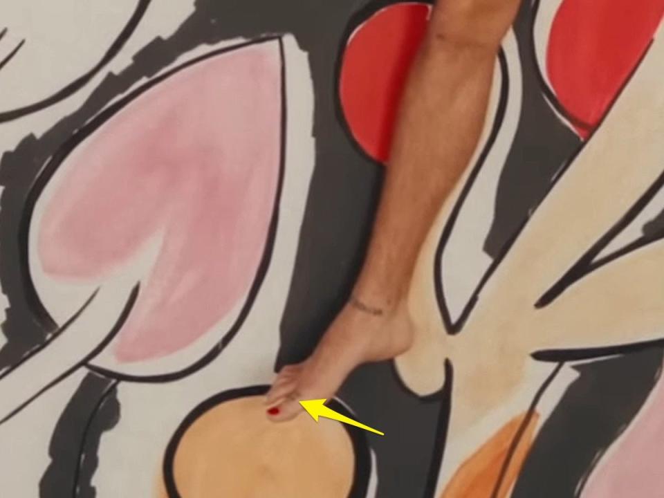 A yellow arrow pointing to a tattoo on Harry Styles' big toe.