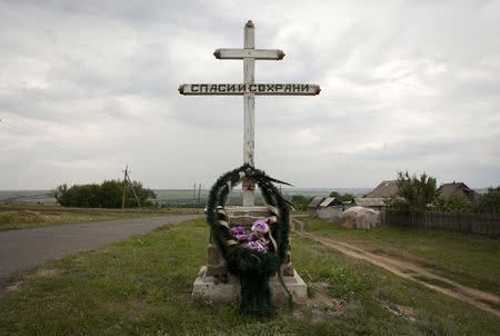 A wreath is placed on a cross with an inscription that reads "Save and protect" next to the site of the downed Malaysia Airlines flight MH17, near the village of Hrabove (Grabovo) in Donetsk region, eastern Ukraine, July 14, 2015. REUTERS/Kazbek Basayev