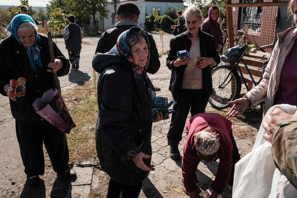 Local residents take food distributed by a Ukrainian soldier in the town of Yampil, in Donetsk region, in this October 6, 2022 photo taken amid the Russian invasion of Ukraine. (Credit: Yasuyoshi CHIBA / AFP)