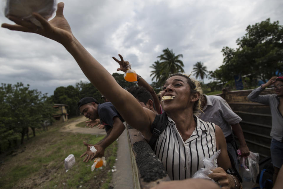 In this Nov. 2, 2018 photo, Honduran transgender Teresa Perez, who is part of a group of 50 or so LGBTQ migrants traveling with the migrant caravan hoping to reach the U.S. border, catches a sandwich tossed by a local, while riding in the back of a truck on the road to Sayula, Mexico. The caravan has traveled more than 1,000 miles from its origin in San Pedro Sula to the central highlands of Mexico. (AP Photo/Rodrigo Abd)