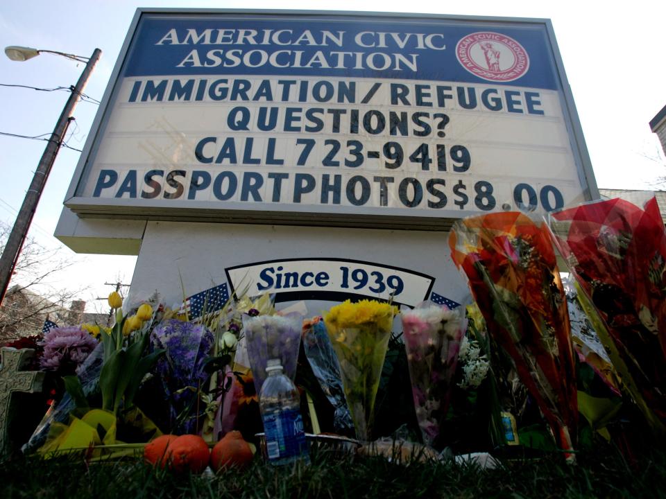 Flowers are seen at the base of a sign in front of the American Civic Association in Binghamton, N.Y., Sunday, April 5, 2009. A gunman, Jiverly Wong, killed 13 people in a rampage at an immigrant community center in Binghamton on Friday before committing suicide.