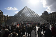 Visitors wait as workers of the culture industry demonstrate outside the Louvre museum Monday, March 27, 2023 in Paris. President Emmanuel Macron inflamed public anger by sending his already unpopular plan to raise the retirement age by two years, from 62 to 64, through parliament without a vote. (AP Photo/Christophe Ena)