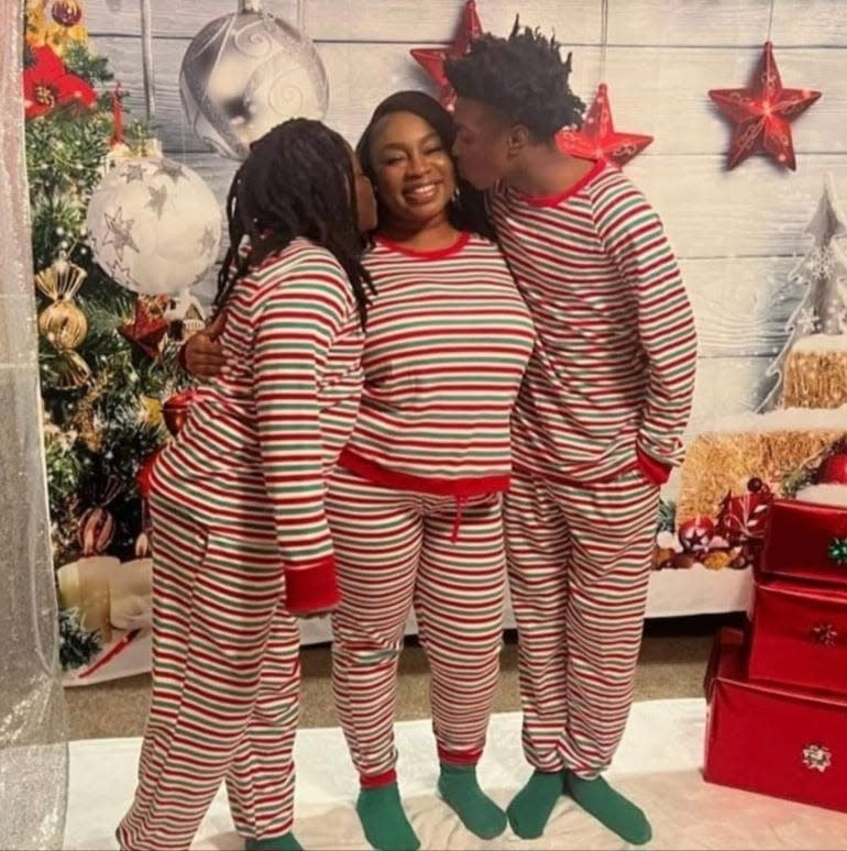 Zaire Person kisses his mother, Khrysten Cunningham, during Christmas 2022. Also pictured is Person's brother, Zah'ki.