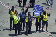 United Airlines employees stand on the tarmac and hold up signs and wave flags during a send-off event for Simone Biles and the U.S. Women's Gymnastics team at the San Francisco International Airport on Wednesday, July 14, 2021. The team was flying to the Summer Olympics in Tokyo. (AP Photo/Eric Risberg)