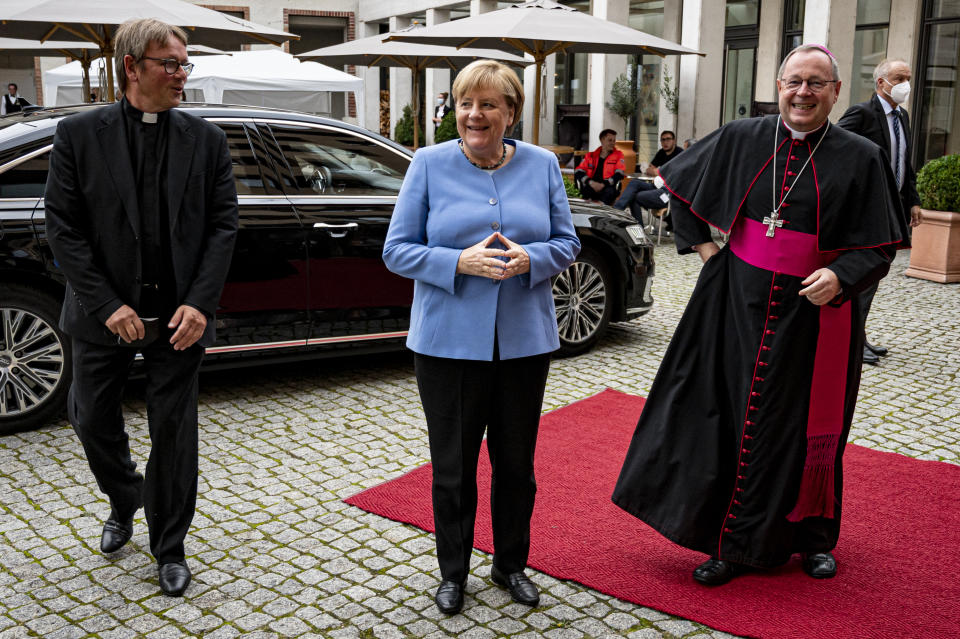 German Chancellor Angela Merkel is greeted by Georg Batzing, right, President of the German Bishops' Conference, and Karl Justen, Head of the Commissariat of the German Bishops, before the St Michael 2021 Annual Reception of the German Bishops' Conference in Berlin, Monday Sept. 27, 2021. (Fabian Sommer/dpa via AP)