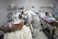 Dr. Joseph Varon, center, visits with Dorothy Webb, left, and her daughter, Tammie, while making his rounds inside the Coronavirus Unit at United Memorial Medical Center, Monday, July 6, 2020, in Houston. Varon says he has worked more than 100 days with barely a rest and normally sleeps just a few hours a night. When he isn't seeing patients or trying to obtain more hospital supplies, he does media interviews to try to warn people to wear masks and take the virus seriously. (AP Photo/David J. Phillip)