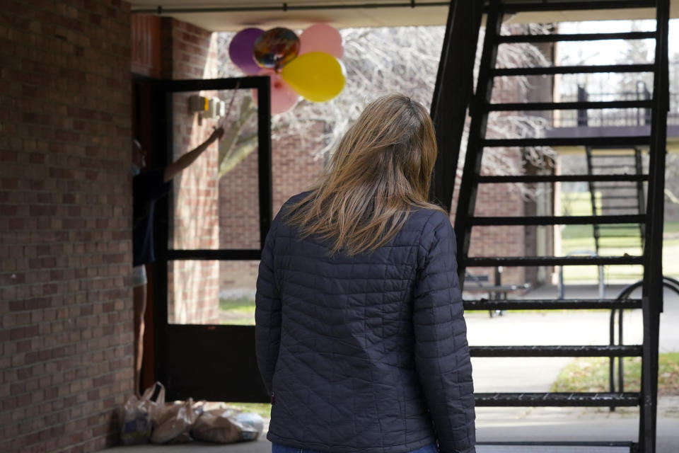 Erica Stowe looks back after delivering groceries and balloons to a student celebrating a birthday, Thursday, Nov. 19, 2020, in Ann Arbor, Mich. A group of parents has come together to help support University of Michigan students while they are sick or quarantining. The group of mostly moms was started and is organized by Sherry Levine of Rye Brook, New York, who's also a mother of a Michigan student. After she spread the word on parent pages on Facebook, local volunteers stepped up to help fulfill student requests by dropping off groceries or supplies. (AP Photo/Carlos Osorio)