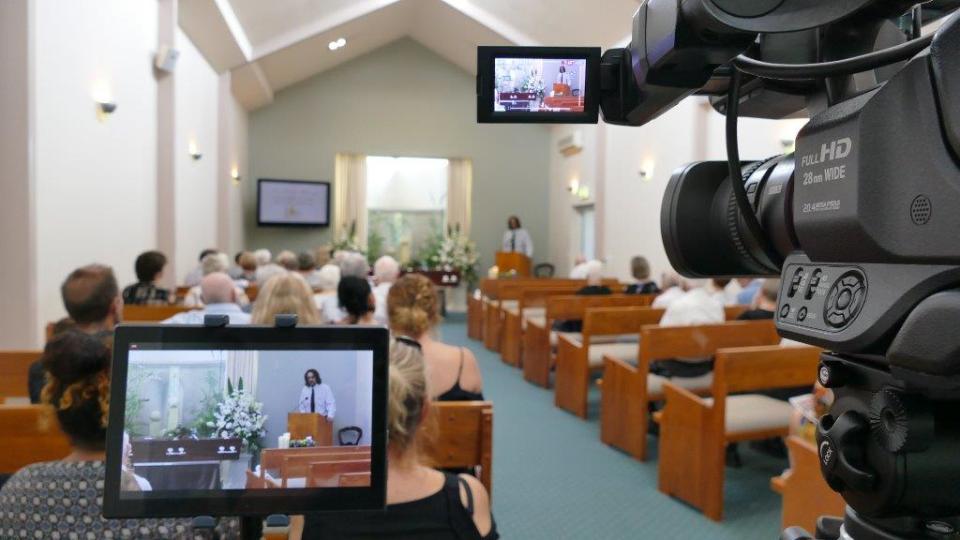 A Queensland funeral service being filmed as a man addresses the gathering.