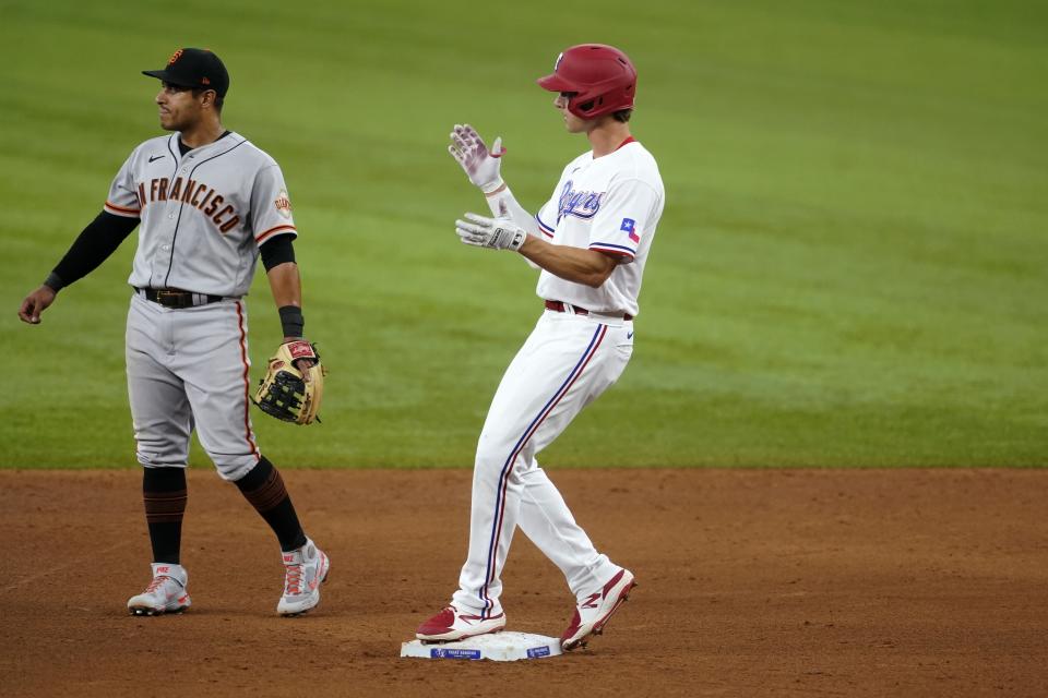 San Francisco Giants second baseman Donovan Solano, left, stands by the bag as Texas Rangers' Eli White celebrates his double in the sixth inning of a baseball game in Arlington, Texas, Wednesday, June 9, 2021. (AP Photo/Tony Gutierrez)