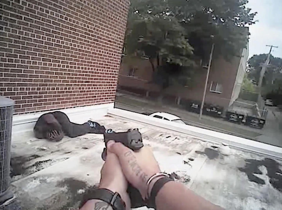 In this Aug. 31, 2017 image made from video provided by the Milwaukee Police Department, Jerry Smith covers his head with his hands after Officer Adam Stahl shot him on the roof of a building in Milwaukee. Smith briefly extended his arms just above his waist to show his empty hands, palms out, then began crouching slowly to the ground. That's when Stahl and Officer Melvin Finkley fired three shots, with one bullet grazing Smith's head and the others striking his abdomen. (Adam Stahl/Milwaukee Police Department via AP)