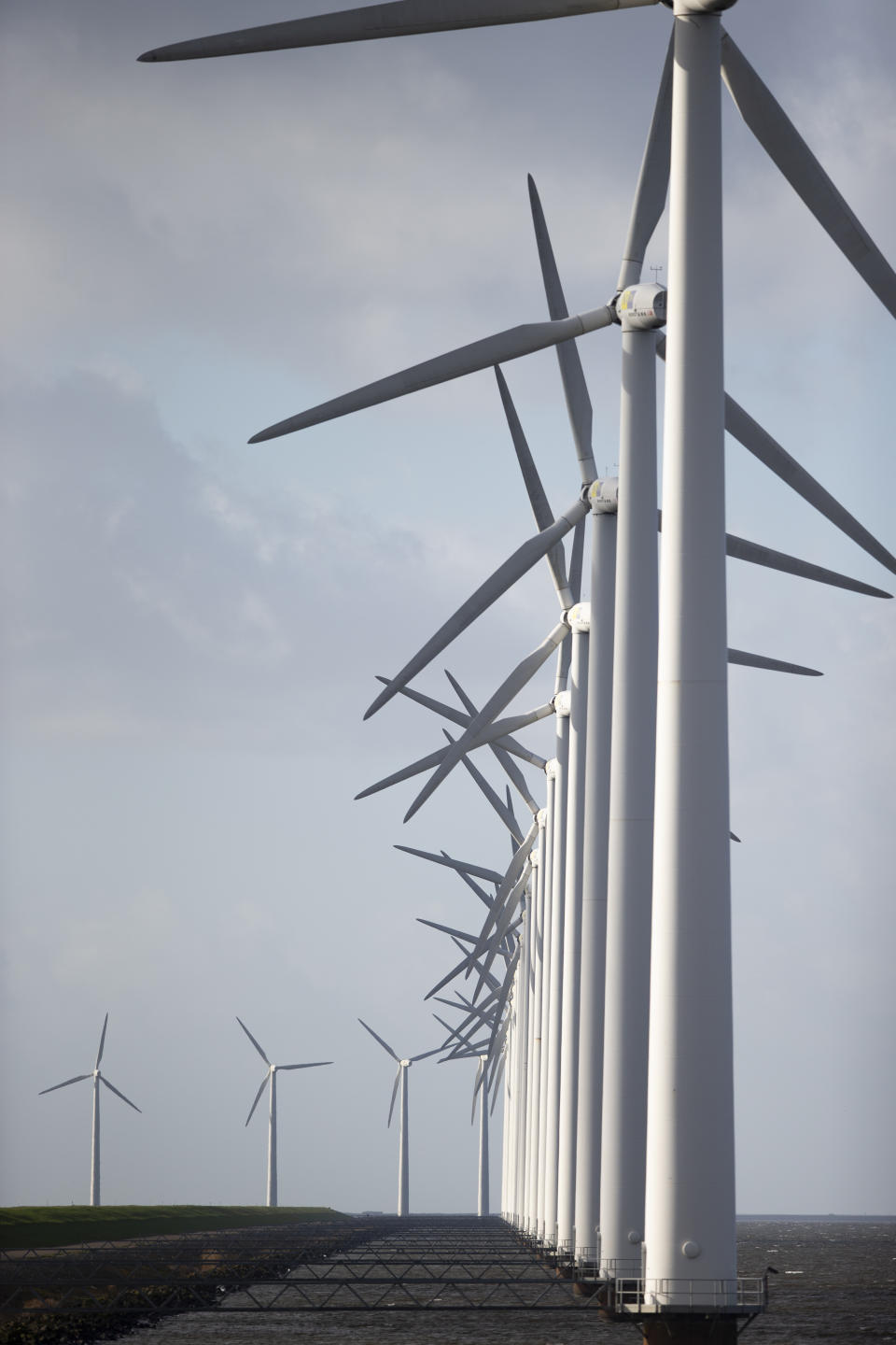 Wind turbines are seen on a dike near Urk, Netherlands, Friday, Jan. 22, 2021. A group of scientists, including five Nobel laureates, called Friday for more action to adapt the world to the effects of climate change, drawing comparisons with the faltering response to the coronavirus crisis, ahead of a major online conference on climate adaptation starting Monday and hosted by the Netherlands. (AP Photo/Peter Dejong)