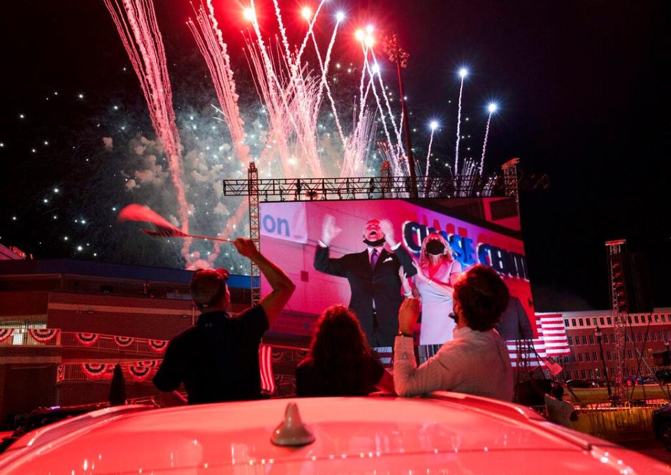 Supporters cheer from their cars as Democratic presidential candidate former Vice President Joe Biden and his wife Jill Biden are seen on a huge monitor as fireworks light up the nigh sky on the fourth day of the Democratic National Convention, Thursday, Aug. 20, 2020, outside of the Chase Center in Wilmington, Del. (AP Photo/Carolyn Kaster)