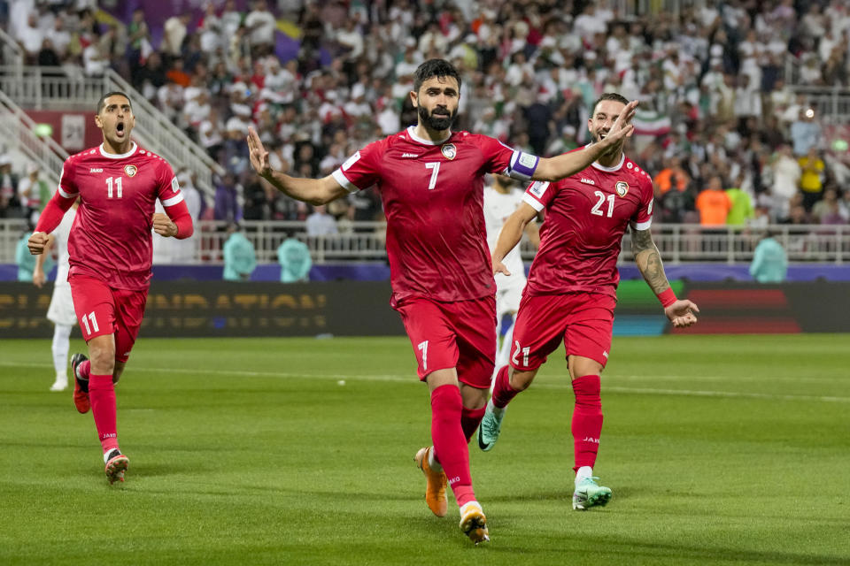 Syria's Omar Khrbin, center, celebrates after scoring his side's opening goal from a penalty spot during the Asian Cup Round of 16 soccer match between Iran and Syria, at Abdullah Bin Khalifa Stadium in Doha, Qatar, Wednesday, Jan. 31, 2024. (AP Photo/Aijaz Rahi)