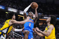 Oklahoma City Thunder guard Shai Gilgeous-Alexander (2) shoots between Indiana Pacers guard Andrew Nembhard, left, and forward Jordan Nwora during the first half of an NBA basketball game in Indianapolis, Friday, March 31, 2023. (AP Photo/Michael Conroy)