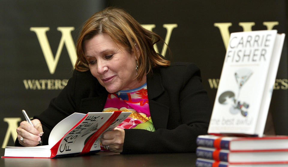 FILE - In this Friday, Feb. 20, 2004 file photo, author Carrie Fisher autographs her new book "The Best Awful" at a promotional event in London. On Tuesday, Dec. 27, 2016, a publicist said Fisher has died at the age of 60. (AP Photo/John D. McHugh, File)