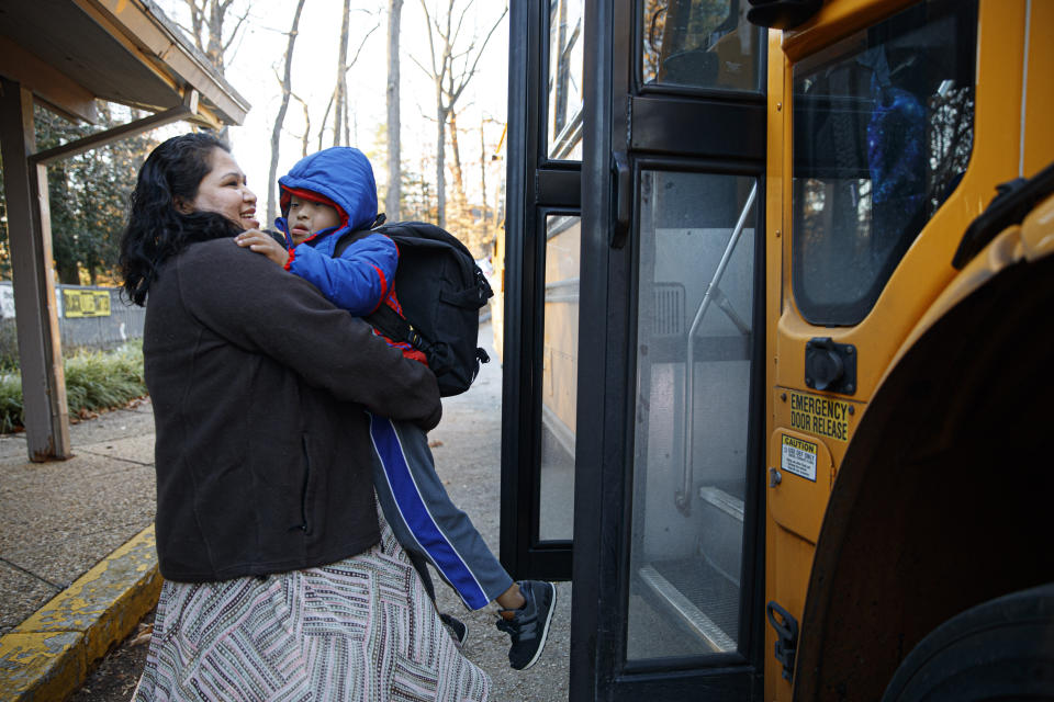 Rosa Gutierrez Lopez, from el Salvador, left, greets her son John, 7, who has Down syndrome, as he gets off the school bus at Cedar Lane Unitarian Universalist Church where the family is living in Bethesda, Md., Thursday, Dec. 5, 2019. Gutierrez Lopez, who a year ago became the first unauthorized immigrant to get refuge inside a religious institution in the Washington area has now been living in sanctuary for a year due to a deportation order. (AP Photo/Jacquelyn Martin)