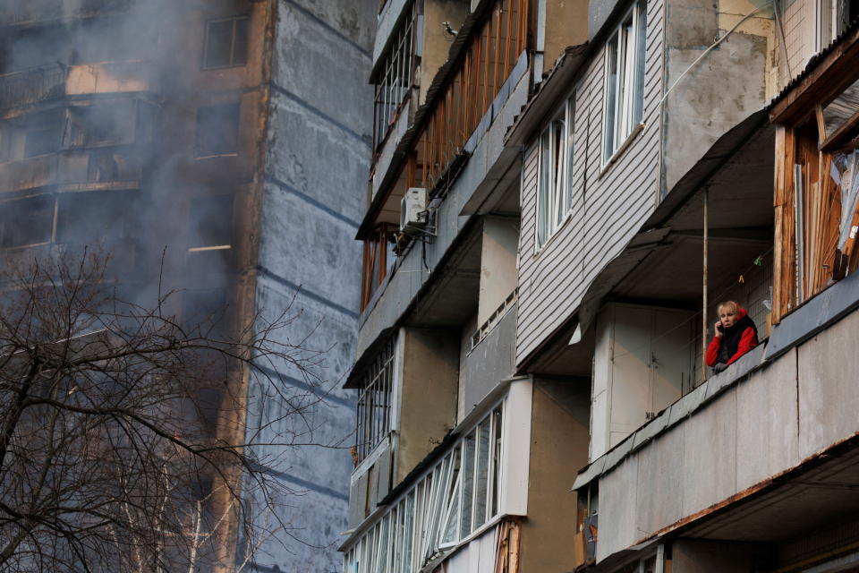 A woman stands in a balcony next to a residential building that was hit by shelling as Russia's attack on Ukraine continues, in Kyiv, Ukraine March 15, 2022. REUTERS/Thomas Peter