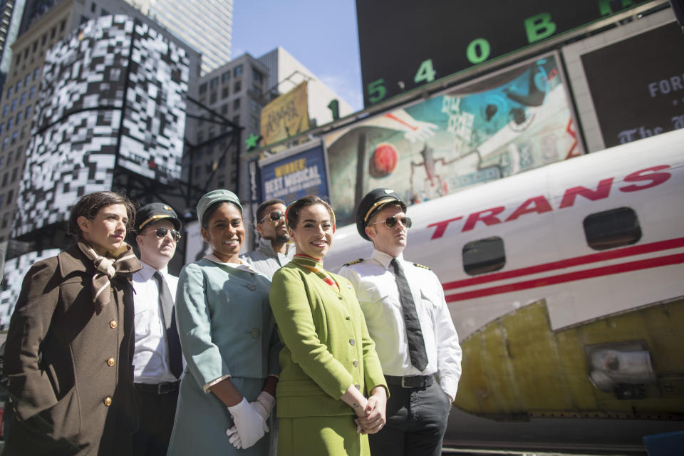 Actors dressed as pilots, flight attendants and mechanics from the 1960s and 70s are seen next to a Lockheed Constellation L-1649A Starliner, known as the "Connie, is parked in New York's Times Square during a promotional event, Saturday, March 23, 2019, in New York. The vintage commercial airplane will serve as the cocktail lounge outside the TWA Hotel at JFK airport, a hotel that promises to bring back "the magic of the Jet Age." (AP Photo/Mary Altaffer)