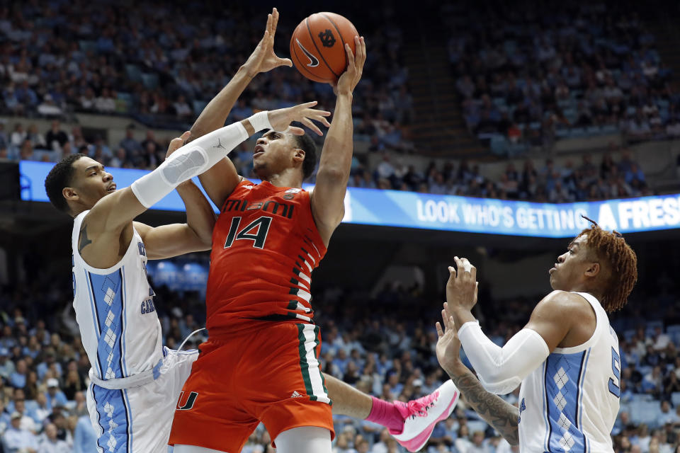 North Carolina forward Garrison Brooks, left, and forward Armando Bacot, right, defend against Miami center Rodney Miller Jr., center, during the second half of an NCAA college basketball game in Chapel Hill, N.C., Saturday, Jan. 25, 2020. (AP Photo/Gerry Broome)