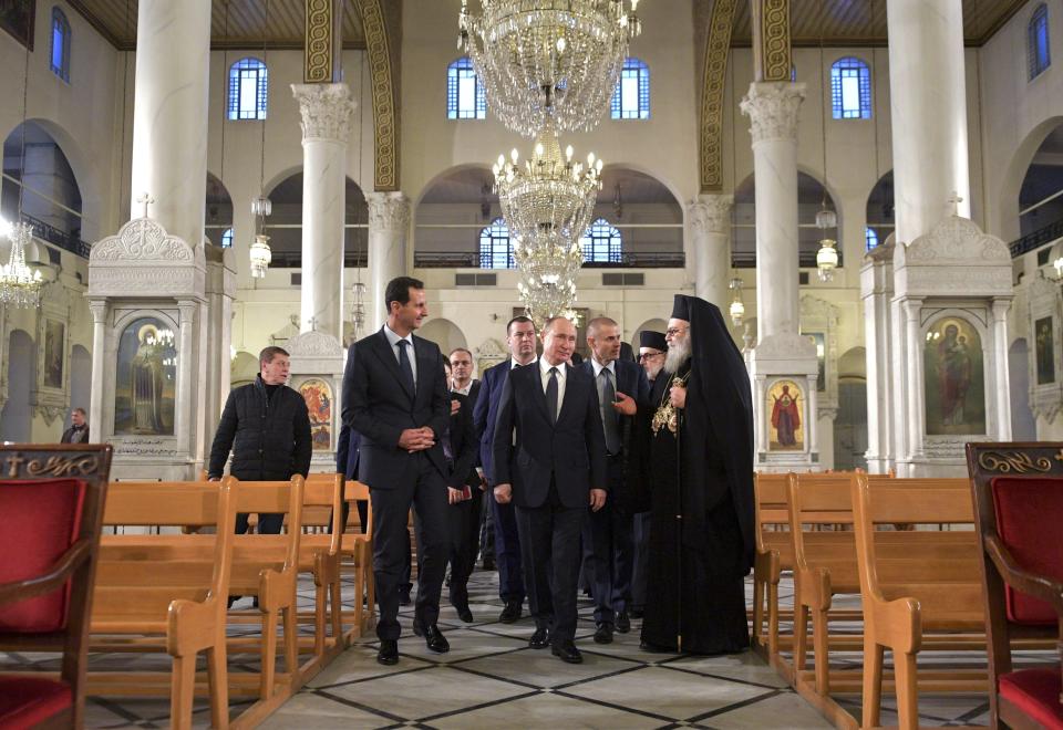 Russian President Vladimir Putin, center, Syrian President Bashar Assad, left, and Greek Orthodox Patriarch of Antioch and All the East, right, talk to each other while visiting an orthodox cathedral for Christmas, in Damascus, Syria, Tuesday, Jan. 7, 2020. Putin has traveled to Syria to meet with President Bashar Assad, a key Iranian ally. The rare visit Tuesday comes amid soaring tensions between Iran and the United States following the U.S. drone strike last week that killed a top Iranian general who led forces supporting Assad in Syria's civil war. (Alexei Druzhinin, Sputnik, Kremlin Pool Photo via AP)