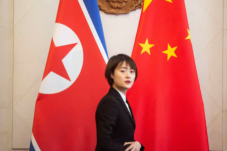 A Chinese hostess walks past North Korean and Chinese flags before the meeting between North Korean Foreign Minister Ri Yong Ho and China's Foreign Minister Wang Yi at the Diaoyutai State Guesthouse in Beijing December 7, 2018. Fred Dufour/Pool via REUTERS