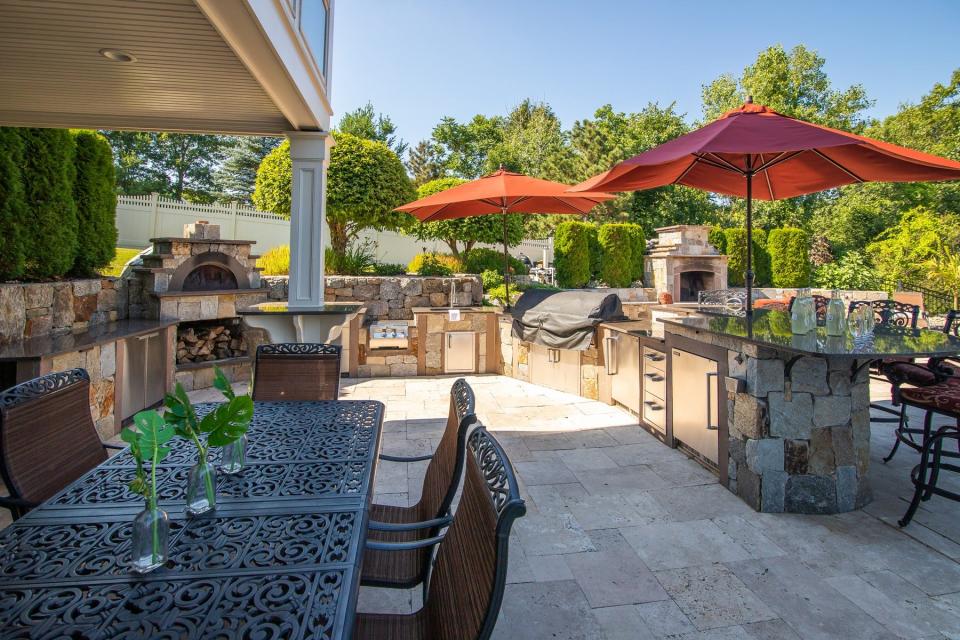 The east-facing backyard features a patio, heated infinity pool, hot tub, full outdoor kitchen with a pizza oven and a fireplace.