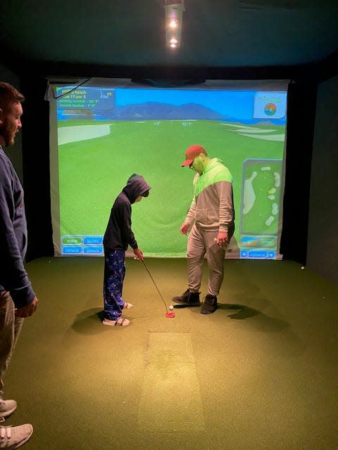 A child takes a turn at one of The Back Nine's golf simulators in Mohegan Lake.