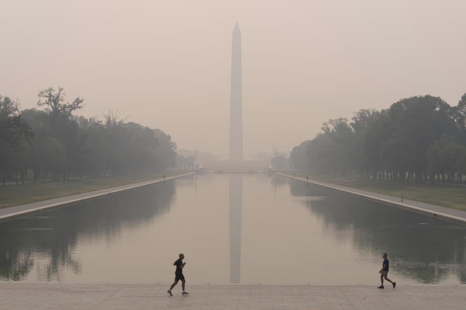 With the Washington Monument in the background and with a thick layer of smoke people run at the National Mall Thursday, June 8, 2023, in Washington. Intense Canadian wildfires are blanketing the northeastern U.S. in a dystopian haze, turning the air acrid, the sky yellowish gray and prompting warnings for vulnerable populations to stay inside. (AP Photo/Jose Luis Magana)