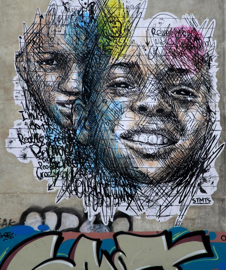 In this photo taken on Monday Feb. 24, 2014, the work 'Moment' by Greek street artist SMTS is seen surrounded by graffiti tags in the Exarchia are of central Athens. The area, known for its compelling street art, is the frequent site of anti-police and anti-government protests and home to a large anarchist community. (AP Photo/Dimitri Messinis)