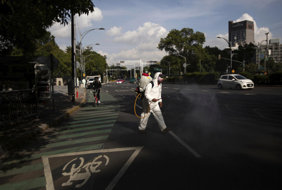 A city worker, dressed in protective gear, sprays disinfectant as a measure to curb the spread of the new coronavirus, on the perimeters of Chapultepec Park which has reopened after being closed for several months, in Mexico City, Wednesday, July 1, 2020. On a four-color alert level, in which red is the worst and green the best, Mexico City downgraded the city’s alert to “orange” even though it has the country’s largest numbers of infections and deaths. (AP Photo/Fernando Llano)