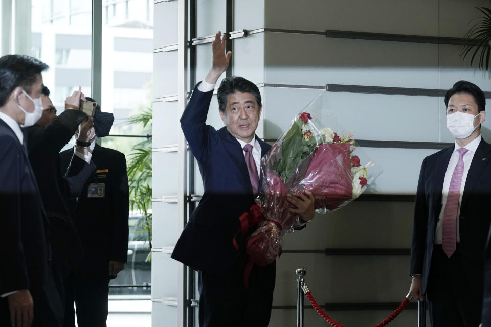 Japan's outgoing Prime Minister Shinzo Abe waves as he leaves the prime minister's office Wednesday, Sept. 16, 2020, in Tokyo. Abe and his Cabinet resigned Wednesday, clearing the way for his successor Yoshihide Suga to take over after parliamentary confirmation later in the day. (AP Photo/Eugene Hoshiko)