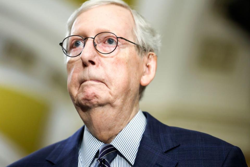 mitch mcconnell wearing a blue suit and striped shit, wears glasses, frowns, and looks off camera