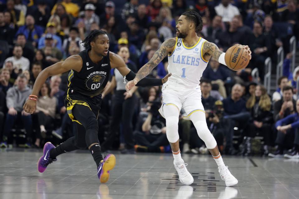 Lakers guard D'Angelo Russell, right, controls the ball in front of Golden State Warriors forward Jonathan Kuminga.