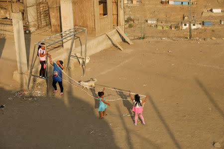 Women and children tie a volleyball net to a goal post before a volleyball match at a makeshift soccer field in Nueva Union shantytown in Villa Maria del Triunfo district of Lima, Peru, April 25, 2018. REUTERS/Mariana Bazo