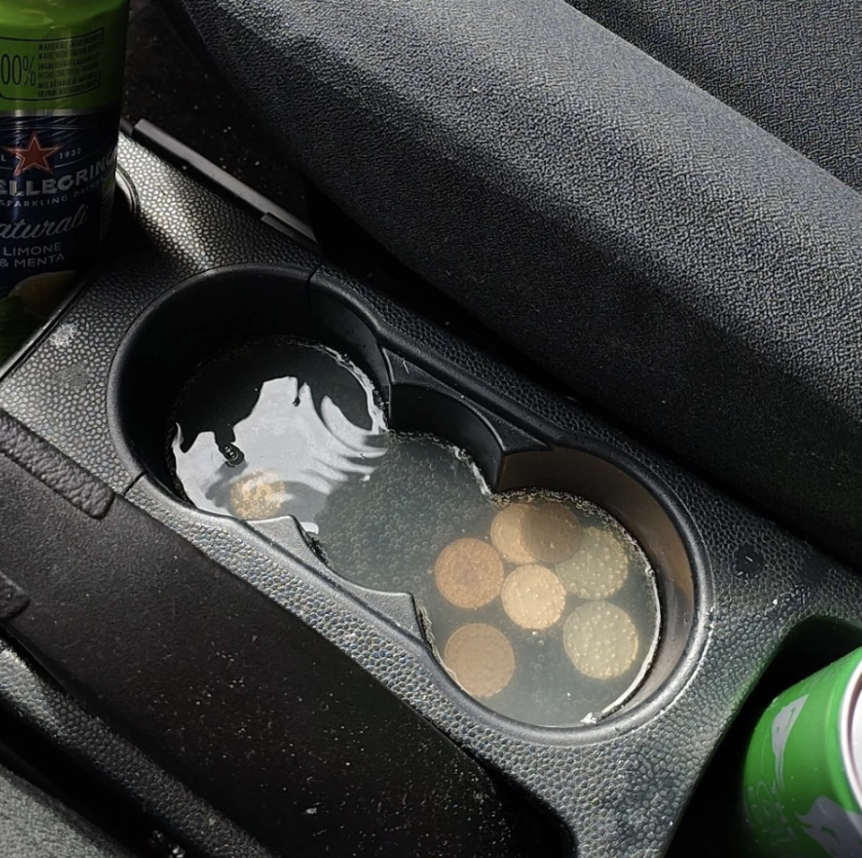 Spilled liquid in car cup holder with coins