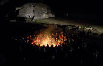 People gather around a sacred fire at the Mayan archeological site of Iximche during a ceremony marking the end of the 13th Oxlajuj B'aktun in Tecpan, Guatemala, early Friday, Dec. 21, 2012. The end of the 13th Oxlajuj B'aktun marks a new period in the Mayan calendar, an event only comparable in recent times with the new millennium in 2000. While the Mayan calendar cycle has prompted a wave of doomsday speculation across the globe, few in the Mayan heartland believe the world will end on Friday. (AP Photo/Moises Castillo)