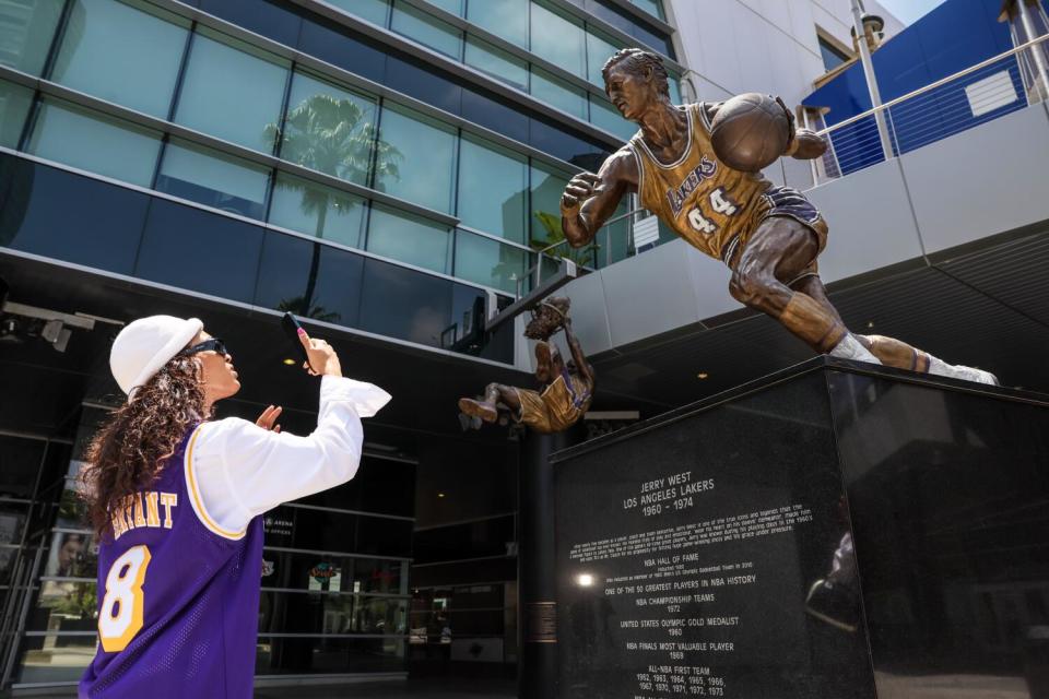 Sankara XT pauses to photograph a statue of Jerry West at the Crypto.Com Arena after hearing the news of his death on Wednesday.