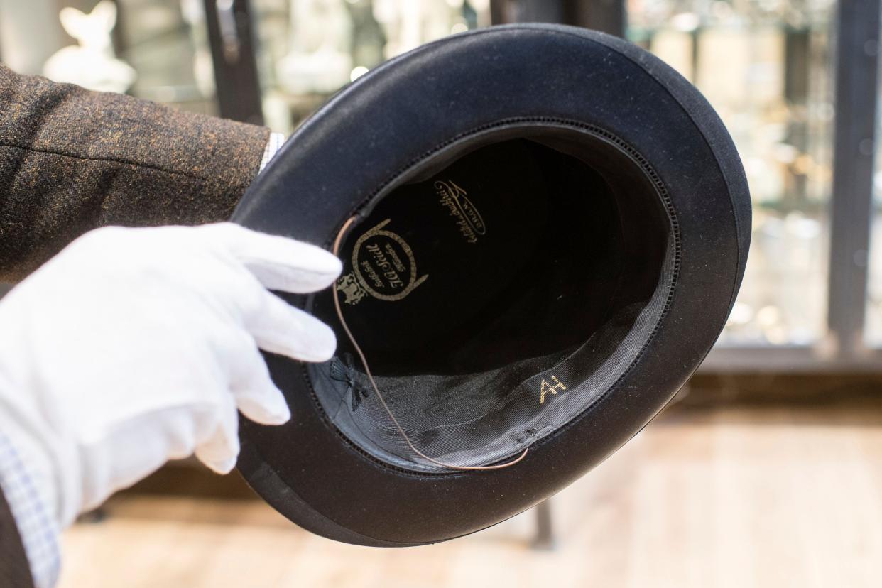 A man holds a hat with the initials of Adolf Hitler prior to an auction in Grasbrunn, Germany, Wednesday, Nov. 201, 2019. A Jewish group has sharply condemned an auction of Nazi memorabilia in Germany.