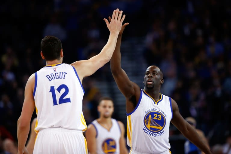Draymond Green (R) of the Golden State Warriors high-fives teammate Andrew Bogut during their NBA game against the Dallas Mavericks, at ORACLE Arena in Oakland, California, on January 27, 2016