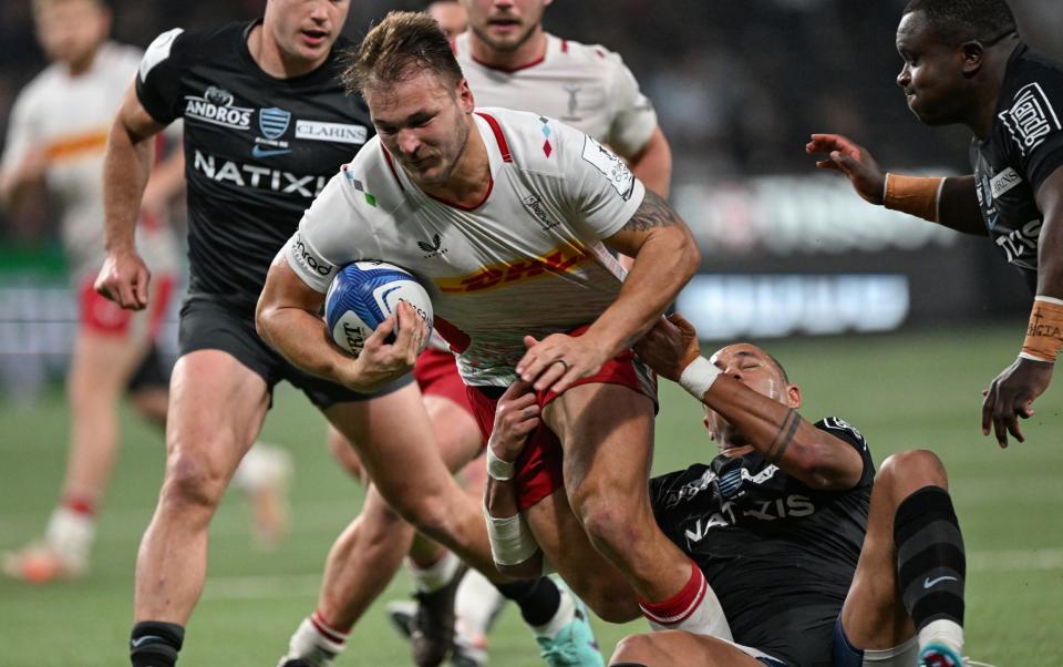 Harlequins' South African centre Andre Esterhuizen (C) is tackled by Racing92's French centre Gael Fickou (2ndR) during the European Champions Cup first round first day group A Rugby Union match between Racing92 and Harlequins at the Paris La Defense Arena in Nanterre on December 10, 2023