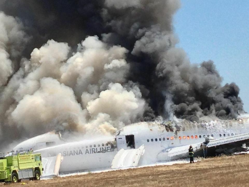 An Asiana Airlines Boeing 777 plane is engulfed in smoke on the tarmac after a crash landing at San Francisco International Airport in California July 6, 2013, in this handout file photo provided by passenger Eugene Anthony Rah, released to Reuters on July 8, 2013. U.S. safety investigators are looking closely at whether an over-reliance on autopilot systems in modern aircraft has degraded human flying skills, increasing the risk of accidents. At a two-day hearing that starts on December 10, 2013, the NTSB will examine if cockpit complacency caused the Asiana Airlines Inc's jetliner with 307 people aboard to crash land at San Francisco International Airport in July, killing three and injuring more than 180. (REUTERS/Eugene Anthony Rah/Handout via Reuters/Files)