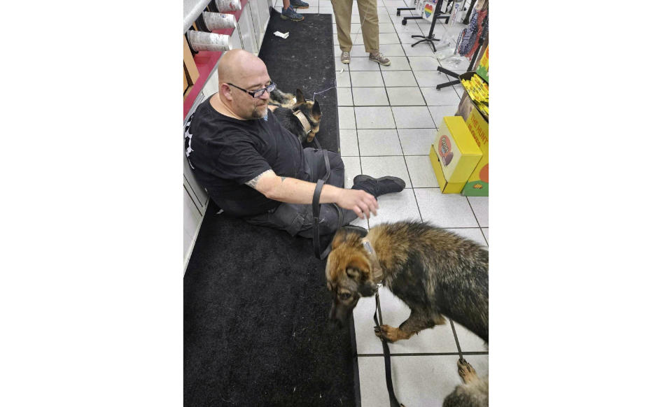 In this photo provided by the Humane Society of Hobart, Ind., a dog suffering from heat-related injury is aided by a man inside the Road Ranger convenience store, in Lake Station, Ind., July 27, 2023. (Jennifer Webber/Humane Society of Hobart, Ind. via AP)