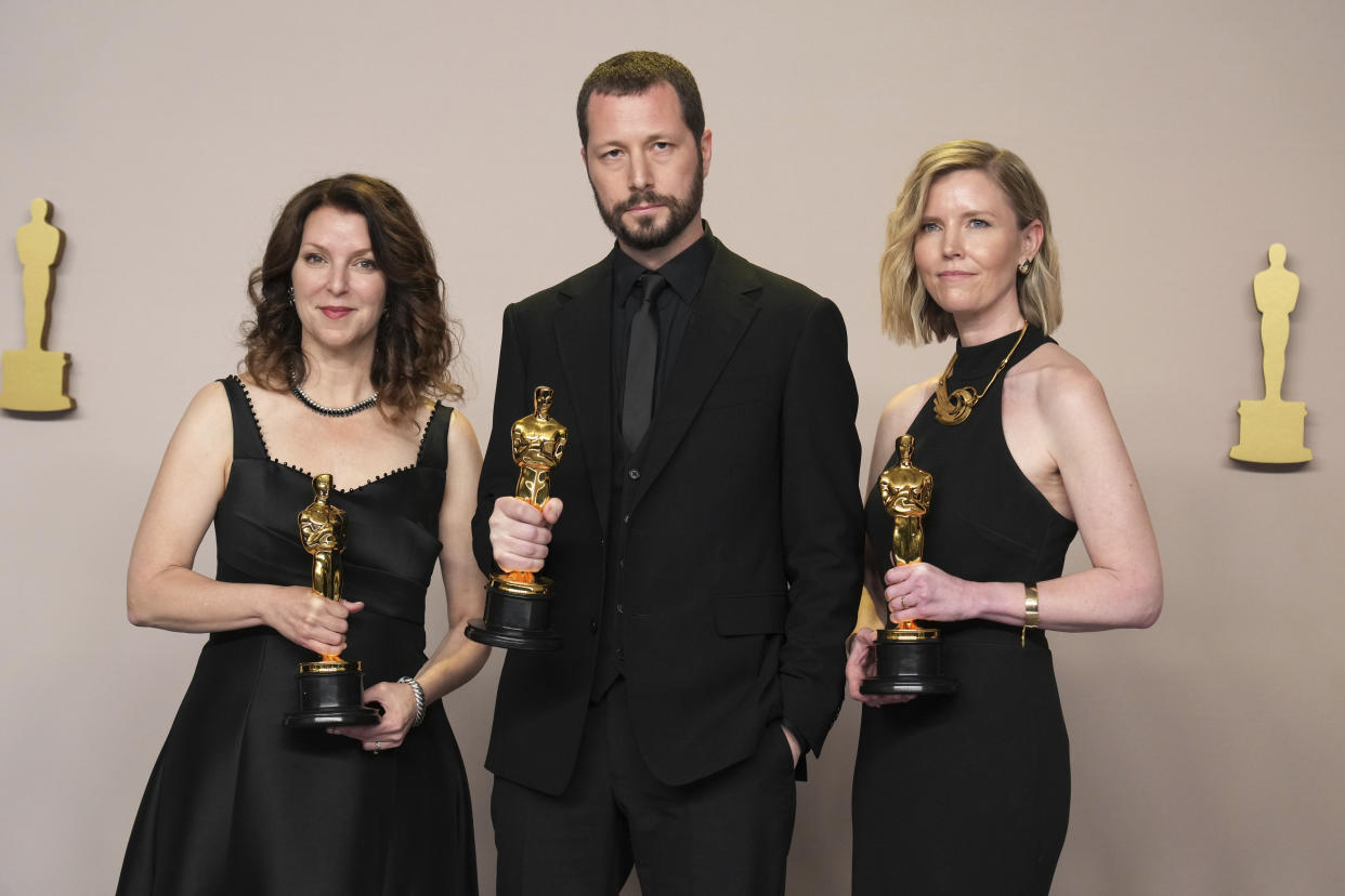 Raney Aronson-Rath (l), Mstyslaw Tschernow und Michelle Mizner posieren im Presseraum mit dem Preis für den besten Dokumentarfilm für 