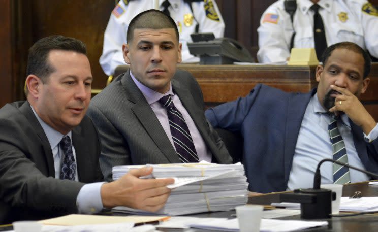 Aaron Hernandez, center, watches as his attorney Jose Baez presents a stack of discovery documents. (AP)