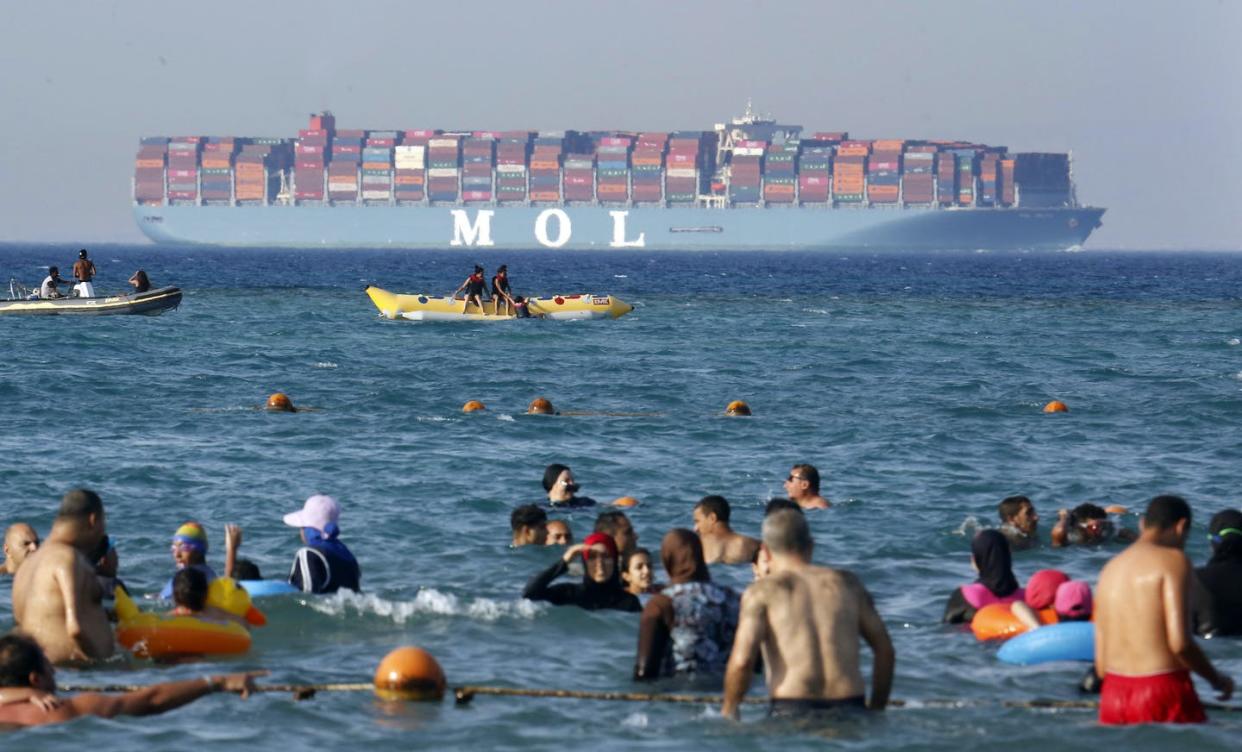 <span class="caption">Beachgoers near Cairo watch a massive container ship sail to the Red Sea.</span> <span class="attribution"><a class="link " href="https://newsroom.ap.org/detail/EgyptDailyLife/586cf490eacb4523953ee2b7b93ef0fe/photo?Query=container%20AND%20ship&mediaType=photo&sortBy=arrivaldatetime:desc&dateRange=Anytime&totalCount=1949&currentItemNo=59" rel="nofollow noopener" target="_blank" data-ylk="slk:AP Photo/Amr Nabil;elm:context_link;itc:0;sec:content-canvas">AP Photo/Amr Nabil</a></span>