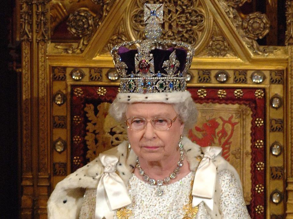 Queen Elizabeth wears the Imperial State Crown as she sits on a throne.